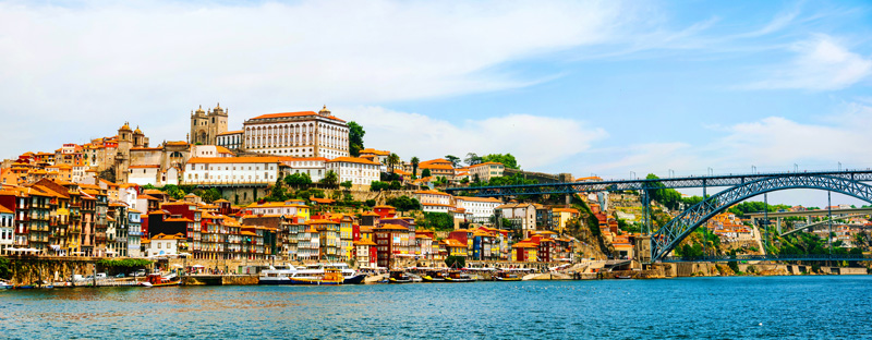 Porto, Portugal. Panoramic view of colorful old houses of Porto, Portugal with Luis I Bridge - a metal arch bridge over Douro River. It is a symbol of the city and a most popular touristic attraction