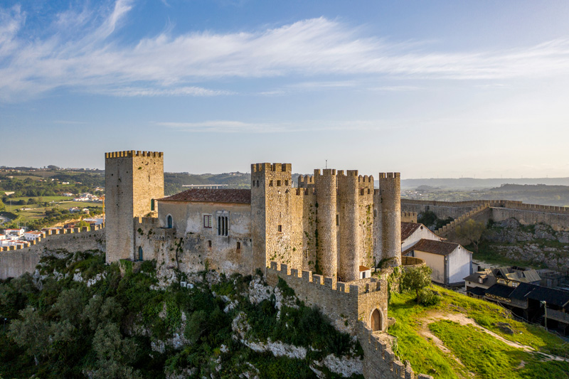 Aerial drone view over Obidos medieval Castle, in Obidos Village, Portugal. Sunset golden hour.